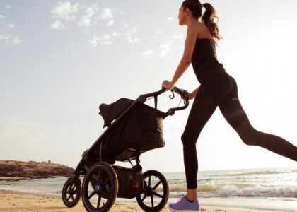 A mom jogging on the beach while pushing a stroller, symbolizing fitness and self-care for busy mothers.