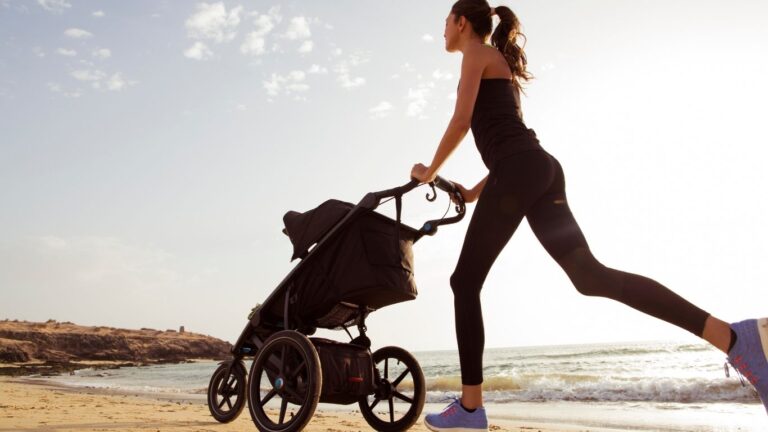 A mom jogging on the beach while pushing a stroller, symbolizing fitness and self-care for busy mothers.