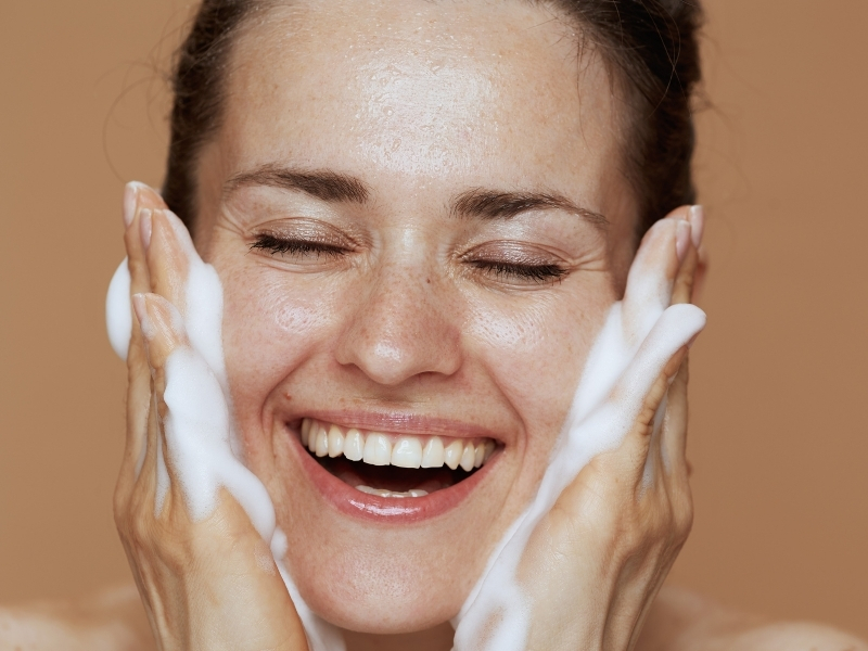 woman washing face with gentle cleanser to avoid stripping skin