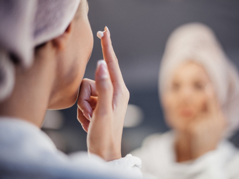 Mature woman smiling while applying retinol cream