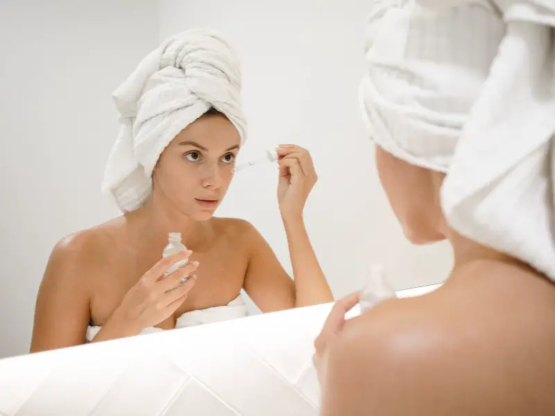 Woman with acne-prone skin applying retinol serum