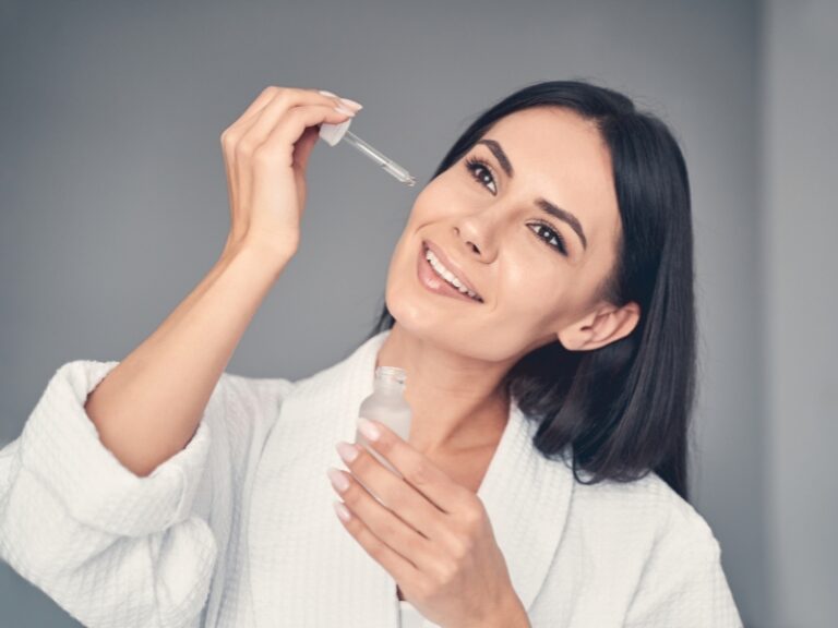 Woman applying night serum for glowing skin.