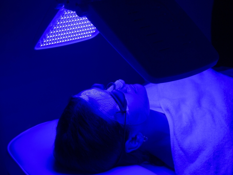 woman using blue light therapy on face