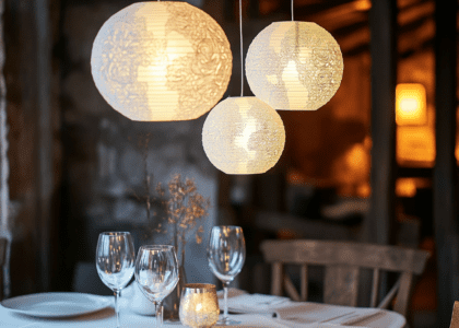 White paper lanterns with intricate patterns hanging from the ceiling of a rustic dining room, creating an elegant ambiance with soft glow illuminating the table settings below.