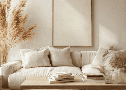 Modern living room featuring a light brown wooden coffee table, a cozy beige sofa, and wall art, decorated with pampas grass for warmth, a stack of books on the coffee table, and soft lighting creating a bright and airy atmosphere.