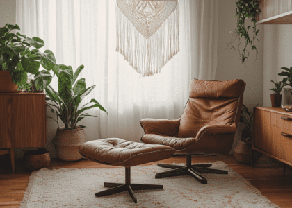 Rustic brown leather armchair and ottoman in earthy-toned room, featuring macramé wall hanging, wooden furniture, large window with white curtains, and decorative plants.