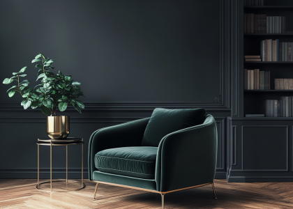 Dark green velvet armchair with brass details beside an elegant side table, featuring a bookcase in the background against dark gray walls, a house plant in a golden pot on a parquet floor, captured in high resolution with professional studio lighting using a Canon EOS R5 camera and macro lens.