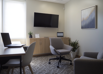 Minimalist office interior design featuring light wood and white accents, natural oak and concrete materials, cozy soft lighting, large mounted TV, two desk chairs with laptop, comfortable armchair, patterned carpet, and wall painting, captured with Sony Alpha camera on Kodak Gold film.