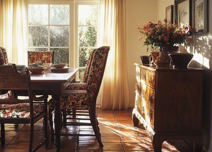 70s dining room with a walnut table, vibrant patterned chairs, soft light from a bay window, terracotta floor tiles, and a vintage sideboard displaying mismatched dishware.