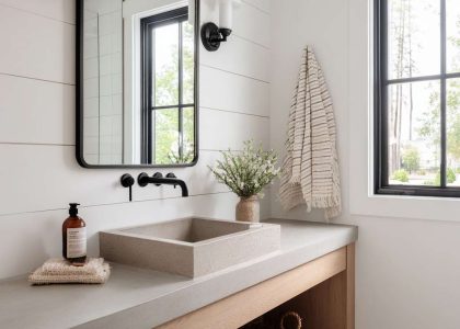 Bright and airy modern farmhouse bathroom featuring crisp white shiplap walls, a natural wood vanity with a concrete top, matte black faucets, and a simple black-framed mirror reflecting natural light, creating an inviting and sophisticated retreat for relaxation.