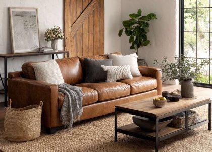 Bright modern farmhouse living room featuring a distressed leather sofa on a textured jute rug, a sleek console table with matte black metal accents, and a large rustic barn door, all bathed in natural light for a warm and inviting atmosphere.